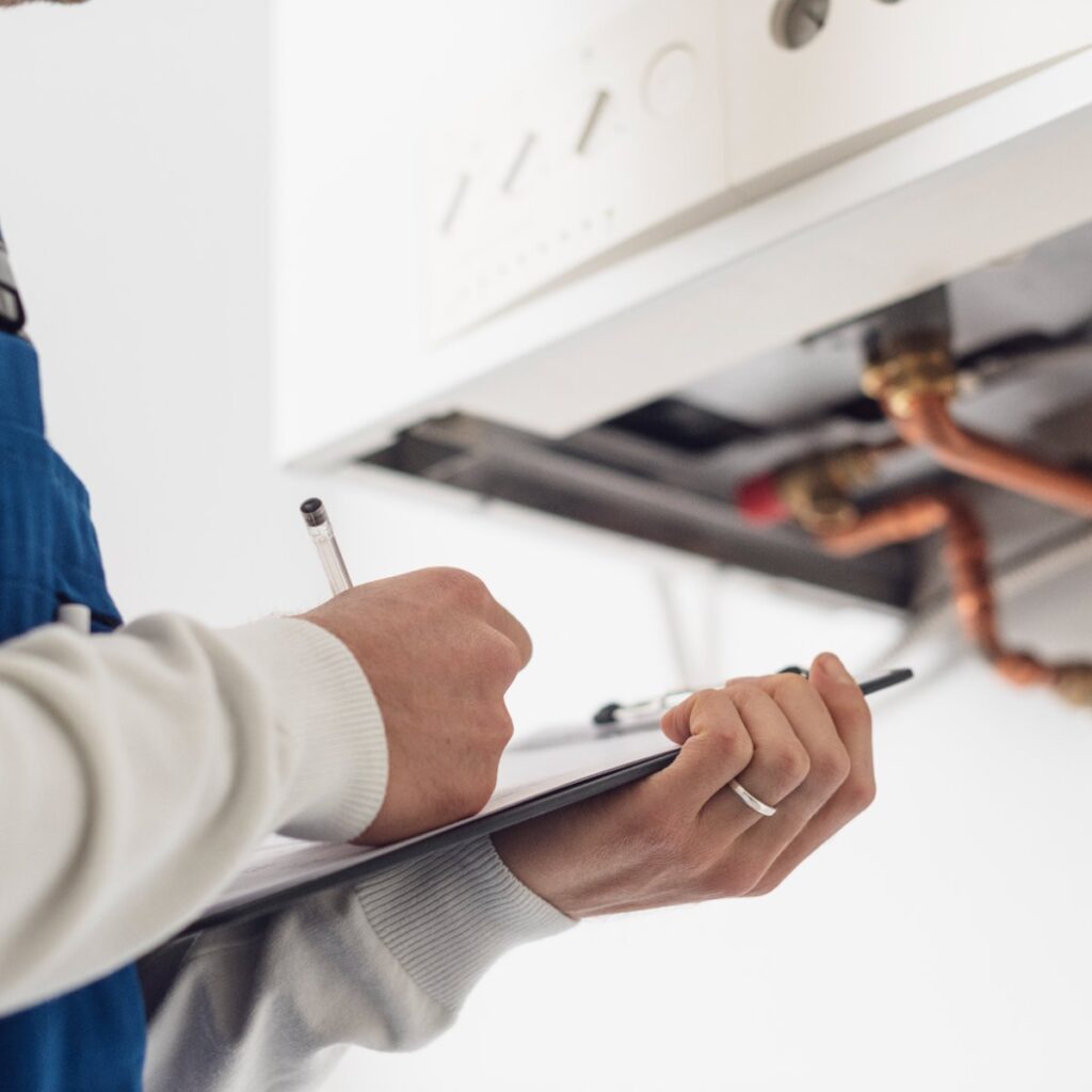 Person holding a clipboard, inspecting water heater